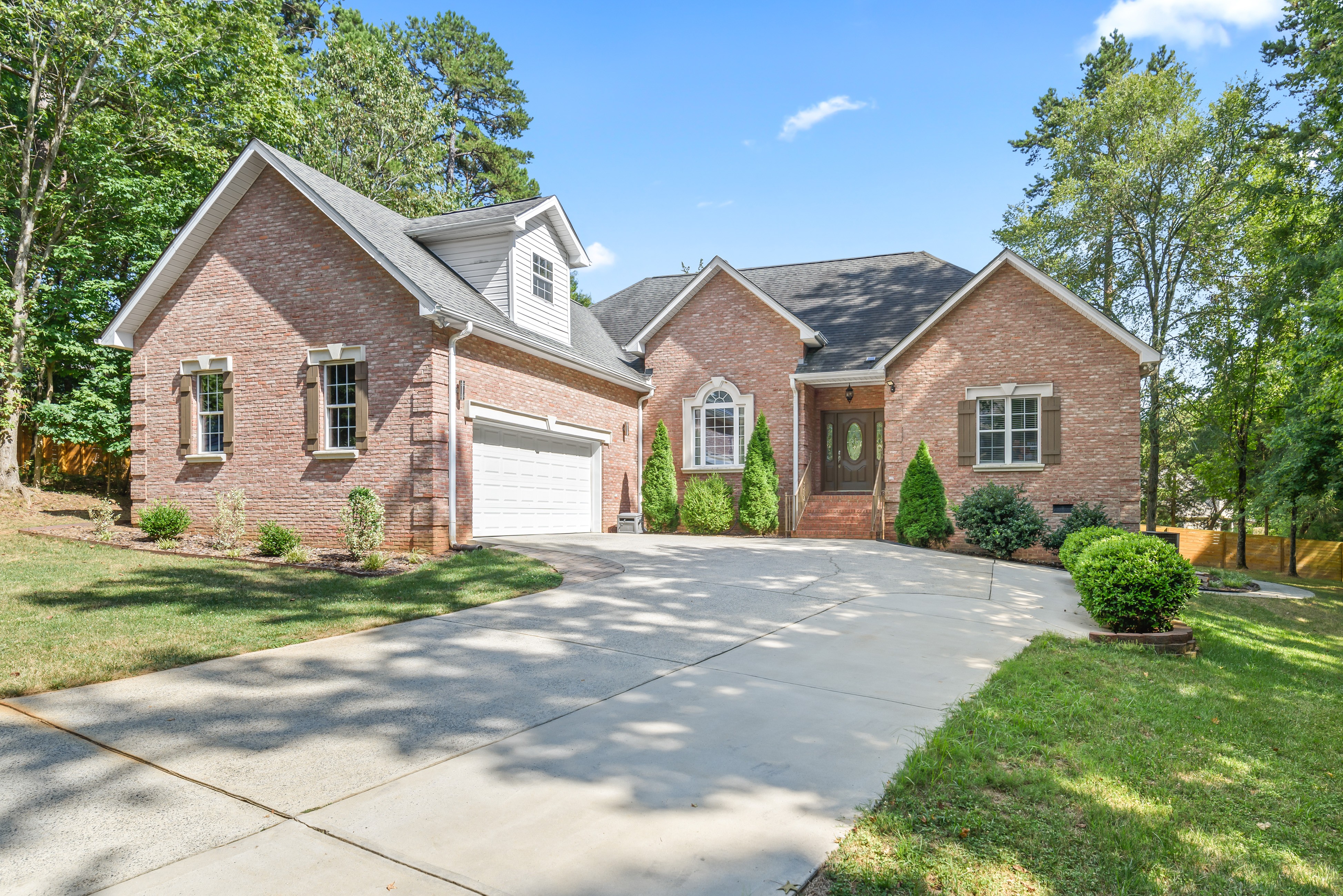 Angled front exterior showing two-car garage, brick facade with shutters, landscaped entry